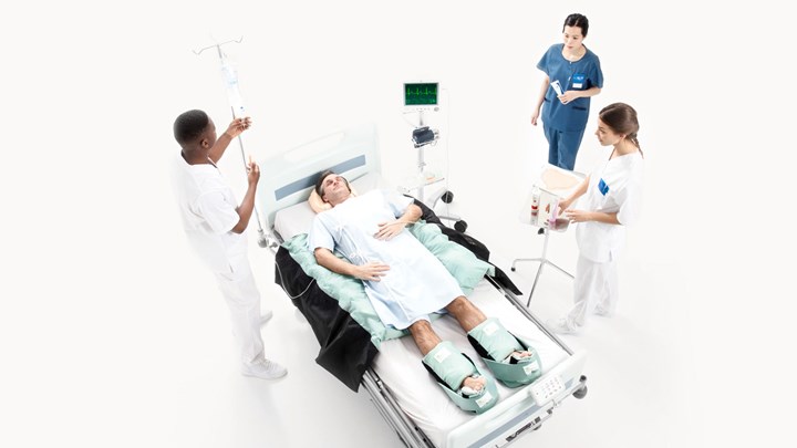 three nurses and one patient in a hospital bed